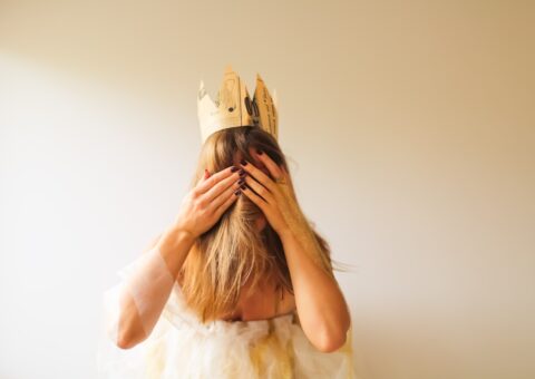 корона на голове волосатой девушки, закрывшей лицо